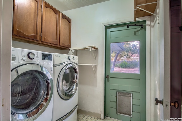 clothes washing area featuring washing machine and dryer, light tile patterned floors, and cabinets