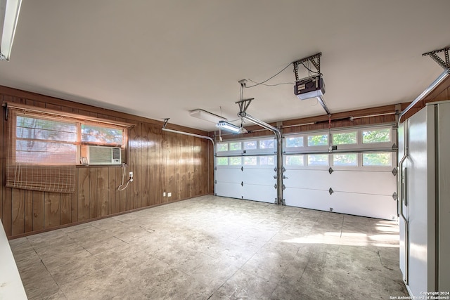 garage with cooling unit, a garage door opener, white refrigerator, and wooden walls