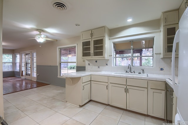 kitchen featuring backsplash, a wealth of natural light, tile counters, and light hardwood / wood-style flooring