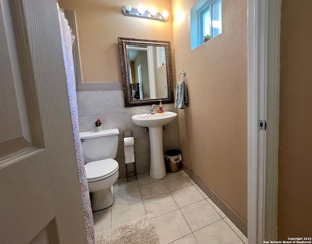 bathroom with tile walls, tile patterned floors, and toilet