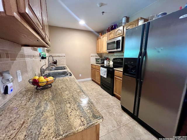 kitchen with light stone countertops, appliances with stainless steel finishes, sink, decorative backsplash, and light tile patterned floors