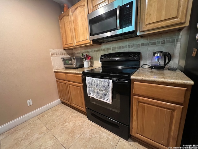 kitchen with tasteful backsplash, black appliances, and light tile patterned floors