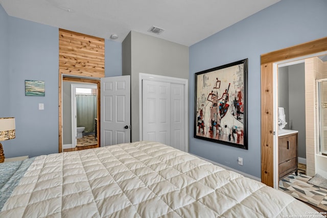 bedroom featuring wood walls, a closet, and ensuite bath