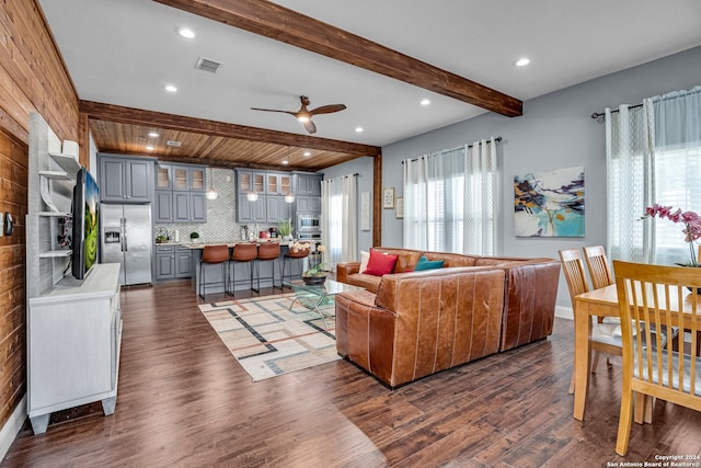 living room featuring beamed ceiling, dark wood-type flooring, and ceiling fan