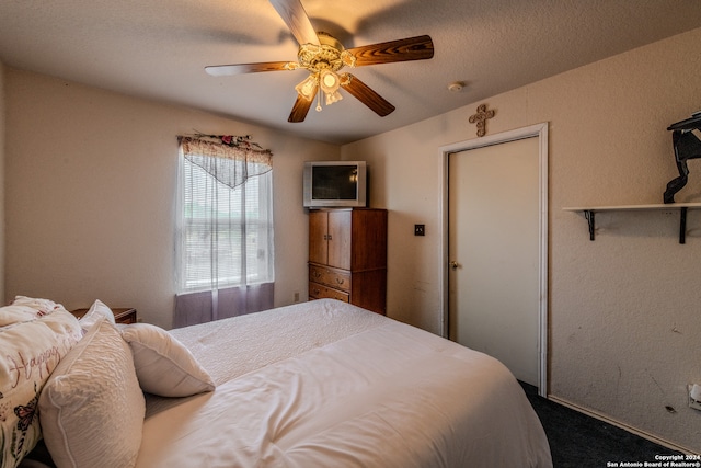 carpeted bedroom featuring ceiling fan and a textured ceiling