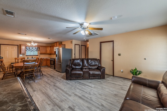 living room with light hardwood / wood-style flooring, a textured ceiling, and ceiling fan with notable chandelier