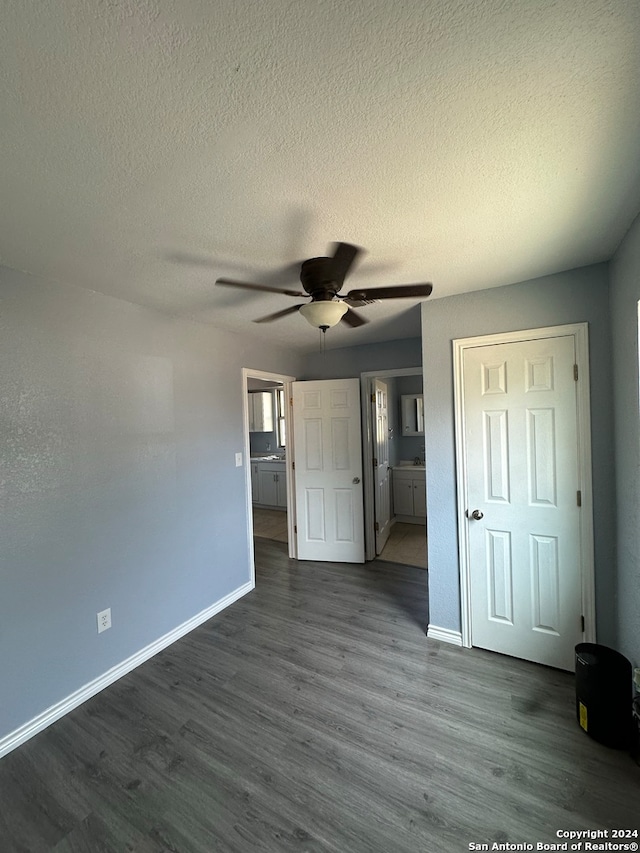 unfurnished bedroom featuring ensuite bath, a textured ceiling, dark hardwood / wood-style floors, and ceiling fan