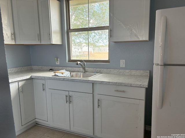 kitchen with sink, white cabinetry, white fridge, and light tile patterned flooring