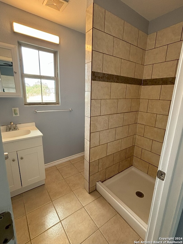 bathroom with vanity, tiled shower, and tile patterned flooring