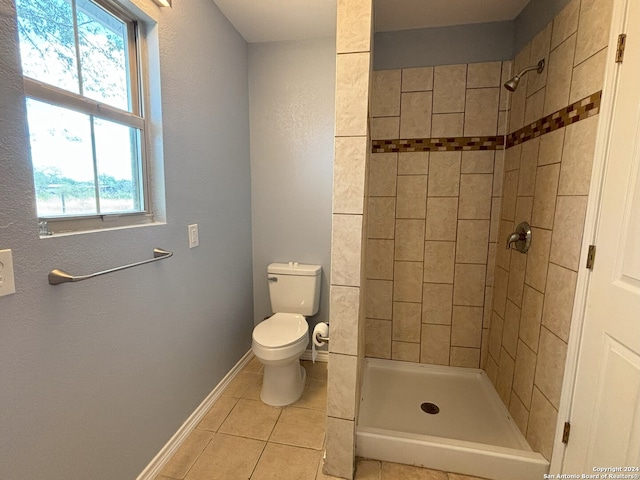 bathroom featuring toilet, a tile shower, and tile patterned floors