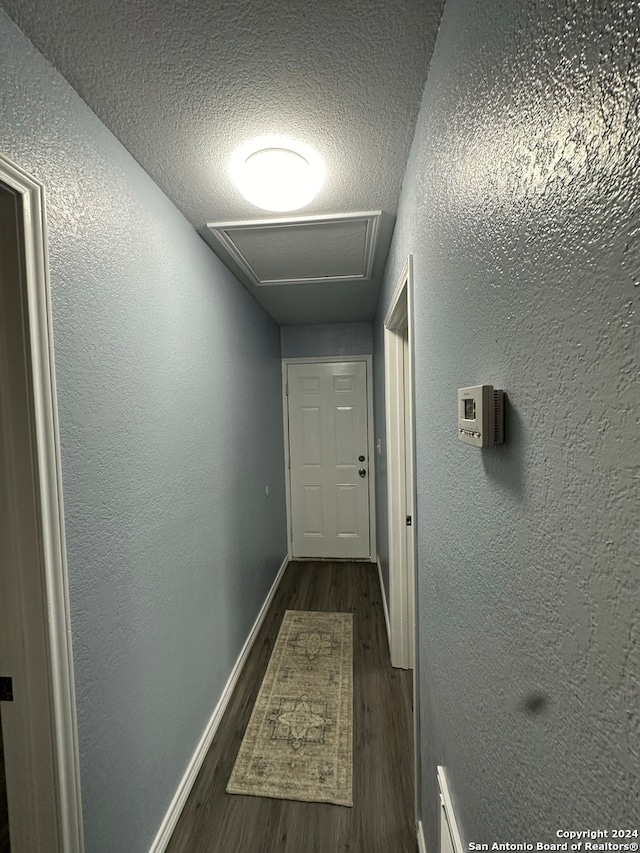 corridor with a textured ceiling and dark hardwood / wood-style flooring