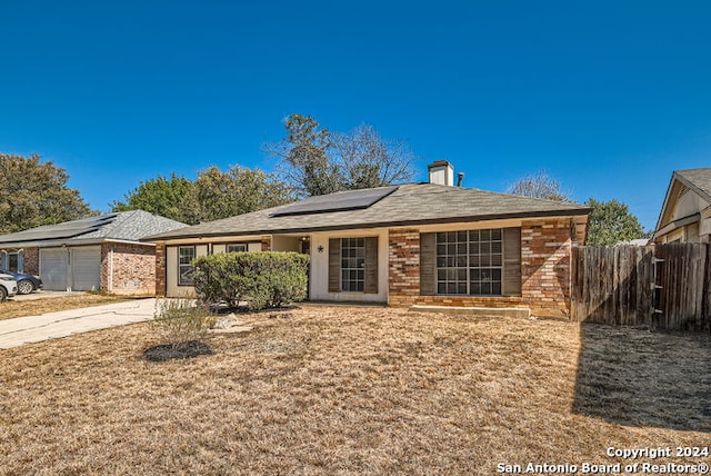 single story home with a garage and solar panels