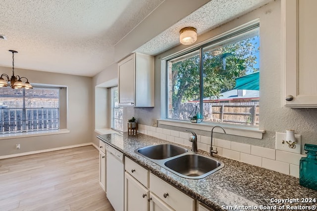 kitchen with white cabinets, hanging light fixtures, light hardwood / wood-style flooring, dishwasher, and sink