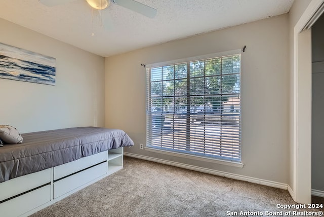 carpeted bedroom with a textured ceiling and ceiling fan