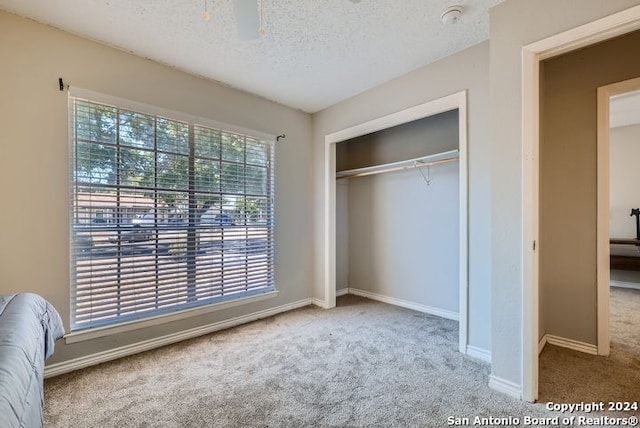 unfurnished bedroom with a closet, ceiling fan, a textured ceiling, and light colored carpet