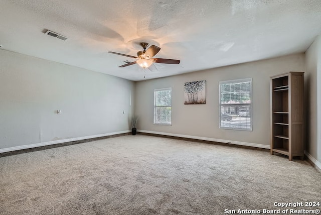 spare room featuring a textured ceiling, carpet, and ceiling fan