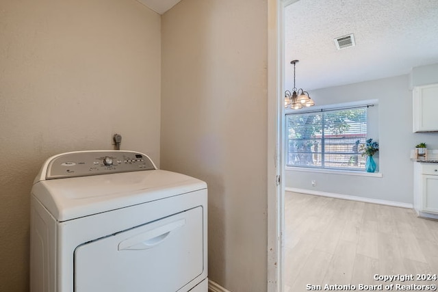 washroom featuring light hardwood / wood-style floors, an inviting chandelier, washer / clothes dryer, and a textured ceiling