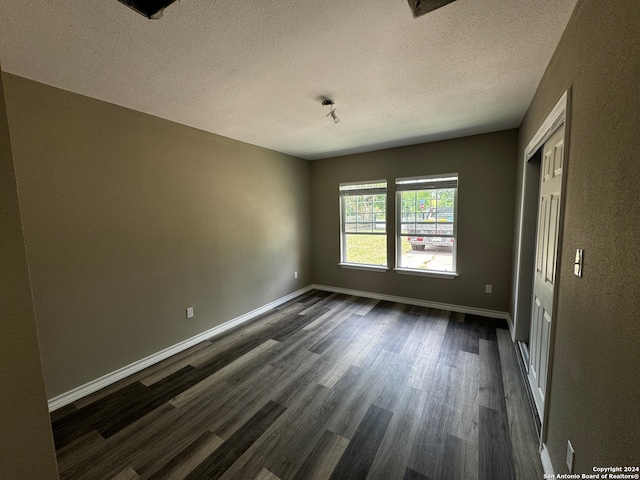 spare room with a textured ceiling and dark hardwood / wood-style flooring