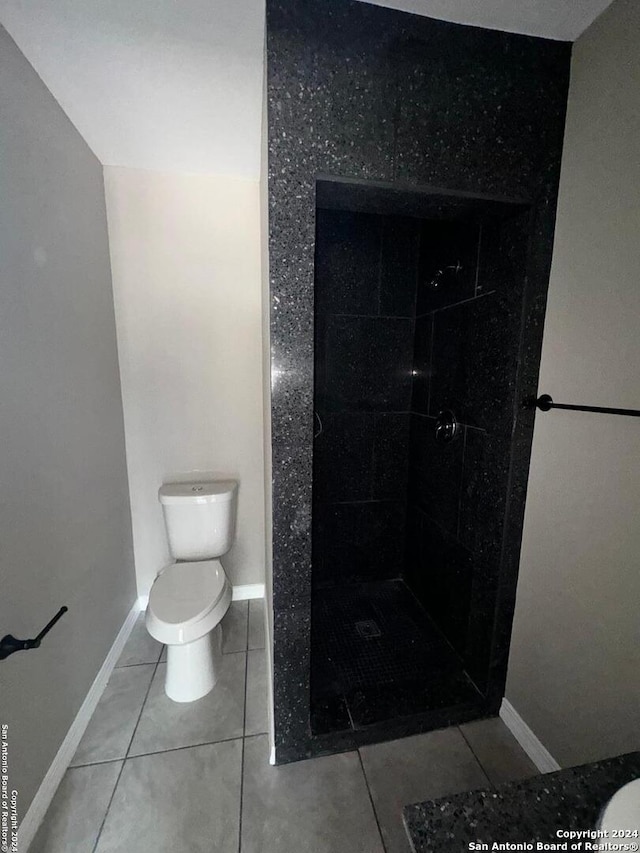 bathroom with tiled shower, toilet, and tile patterned floors