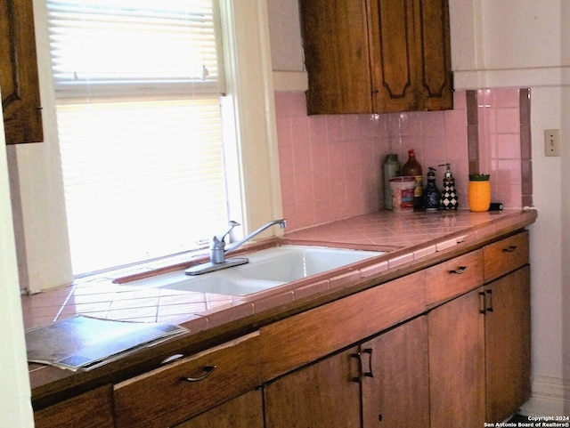 kitchen featuring tile countertops, decorative backsplash, and sink