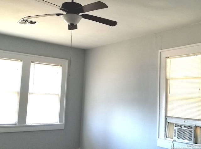 empty room featuring cooling unit, ceiling fan, and a wealth of natural light