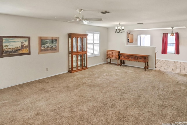 living room with carpet, ceiling fan, baseboards, and a chandelier
