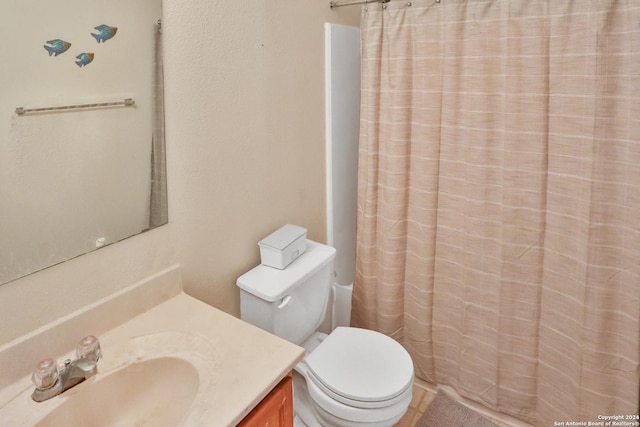 bathroom featuring toilet, vanity, and curtained shower