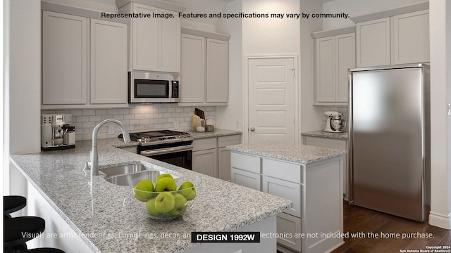 kitchen featuring kitchen peninsula, stainless steel appliances, sink, light stone counters, and dark hardwood / wood-style flooring