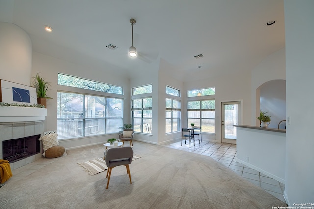 living room featuring light carpet, a tile fireplace, and a high ceiling