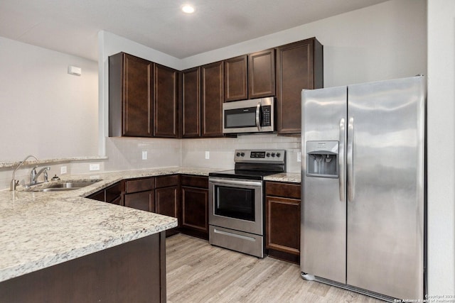 kitchen featuring dark brown cabinetry, sink, light hardwood / wood-style flooring, and appliances with stainless steel finishes