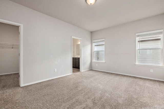 unfurnished bedroom featuring a spacious closet, a closet, carpet floors, and ensuite bathroom