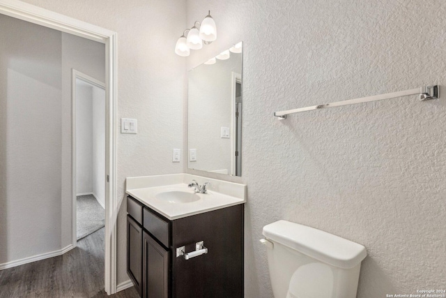 bathroom with toilet, vanity, and hardwood / wood-style flooring