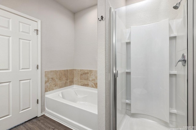 bathroom with wood-type flooring and shower with separate bathtub