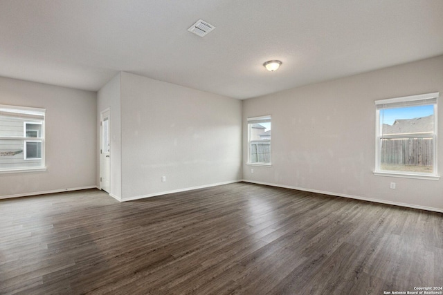 spare room featuring a healthy amount of sunlight and dark hardwood / wood-style flooring