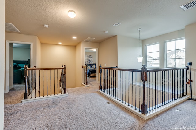 corridor featuring a textured ceiling and carpet flooring