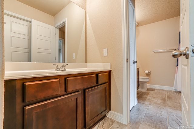 bathroom featuring vanity, toilet, and a textured ceiling