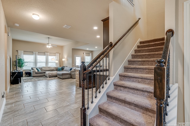 staircase featuring a textured ceiling and ceiling fan