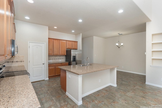 kitchen with a sink, brown cabinetry, an island with sink, stainless steel appliances, and backsplash