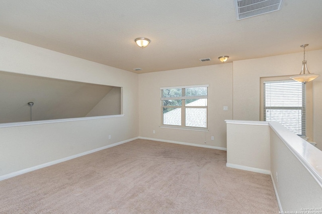 spare room with visible vents, baseboards, and light carpet