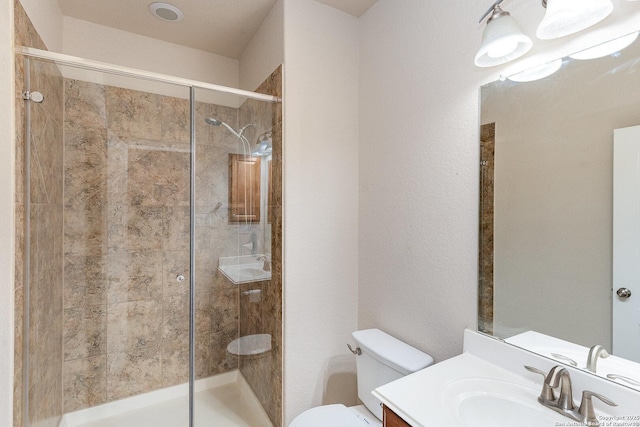 bathroom featuring vanity, a shower stall, and toilet