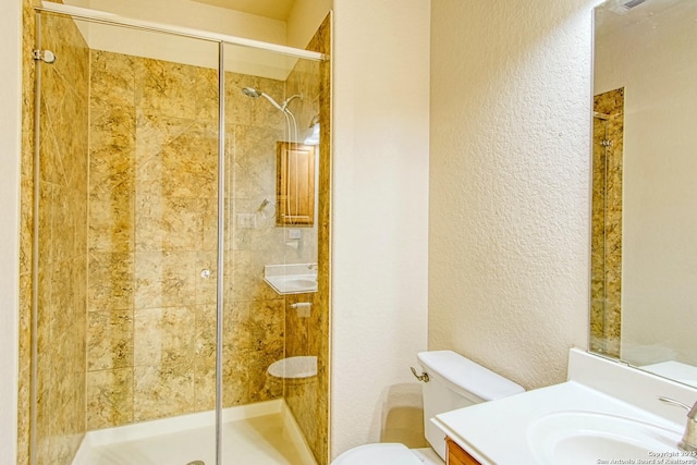 full bath with vanity, a textured wall, a stall shower, and toilet