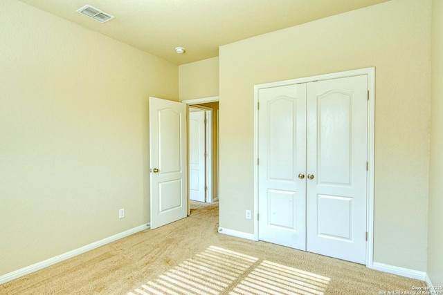 unfurnished bedroom with baseboards, light carpet, a closet, and visible vents