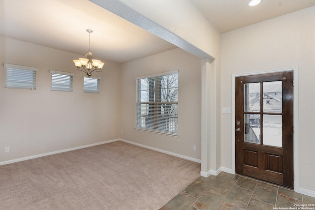 foyer entrance featuring baseboards, dark carpet, and a chandelier