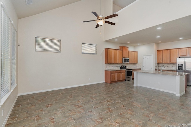kitchen featuring a sink, stainless steel appliances, a ceiling fan, open floor plan, and tasteful backsplash
