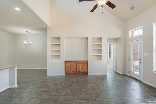 unfurnished living room featuring high vaulted ceiling, built in features, ceiling fan with notable chandelier, baseboards, and visible vents