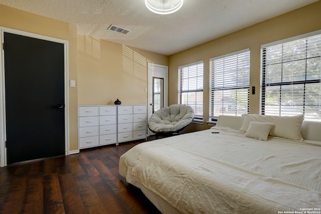 bedroom with dark hardwood / wood-style floors and a textured ceiling