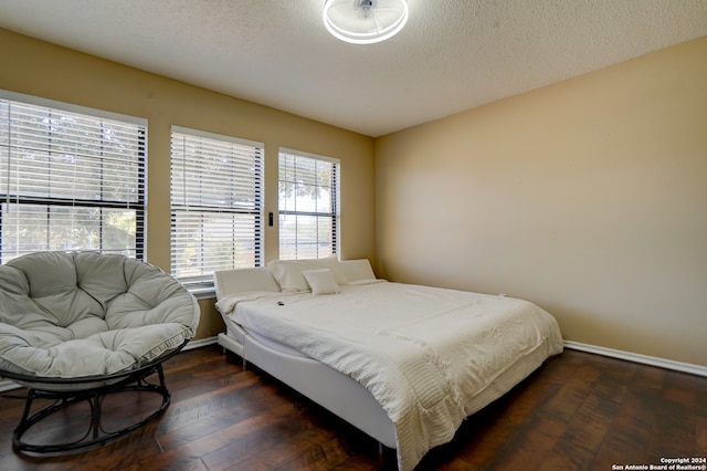 bedroom with a textured ceiling and dark hardwood / wood-style floors