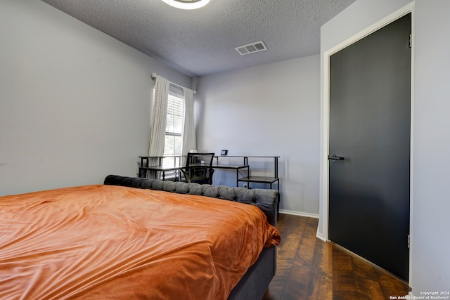 bedroom with a textured ceiling and dark parquet flooring