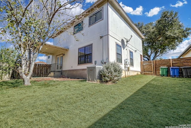 back of house with central AC and a yard