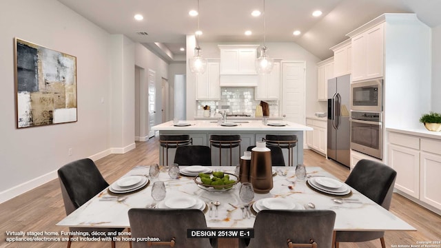 dining room with light hardwood / wood-style flooring and lofted ceiling